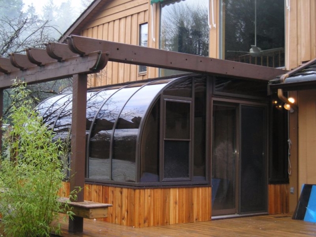 Exterior view of a brown sunroom with wood trim