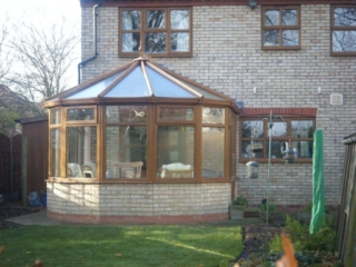 Exterior view of a Victorian-style brown and brick conservatory attached to a home