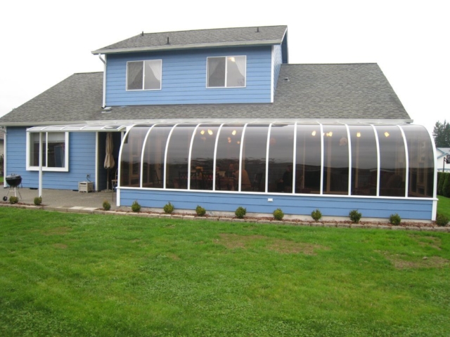 Exterior view of a large curved eave sunroom with an attached patio cover