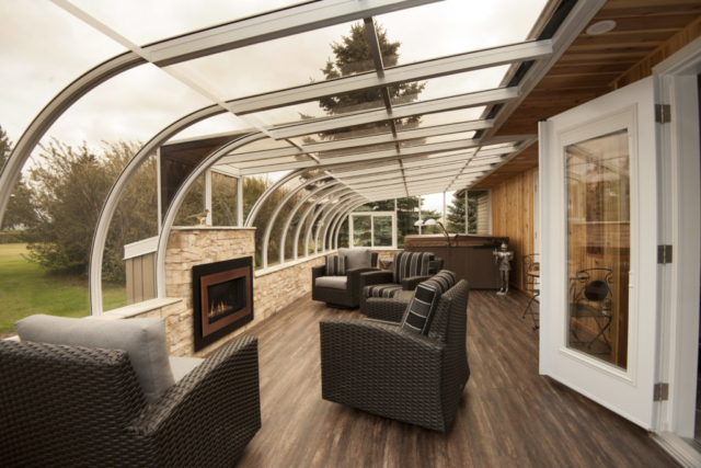 Interior view of a large curved eave sunroom with fireplace and furniture