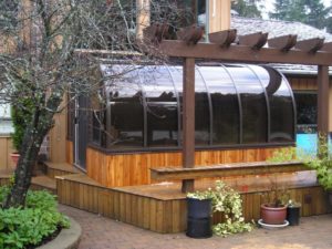 Exterior view of a small dark brown sunroom with wood trim