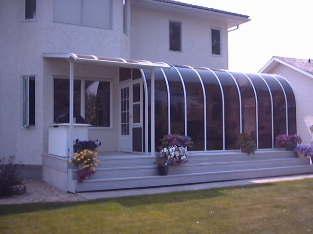 Exterior view of a white curved eave sunroom with dark windows