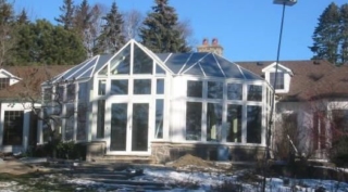 Exterior view of a white Victorian conservatory with a stone foundation